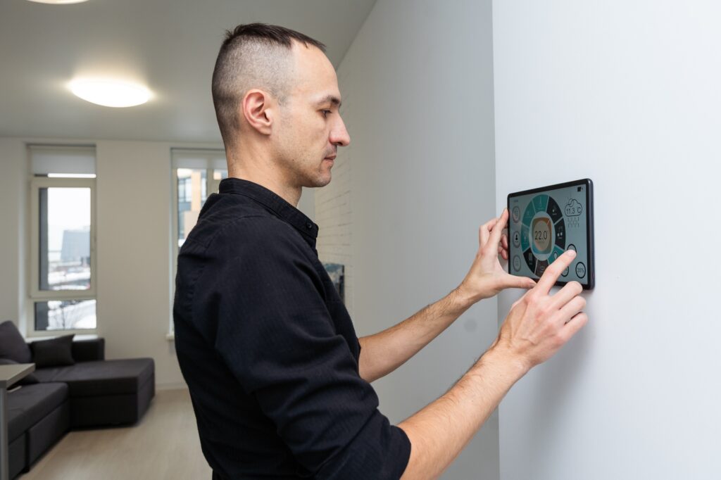 Worker with tablet computer checking alarm system indoors