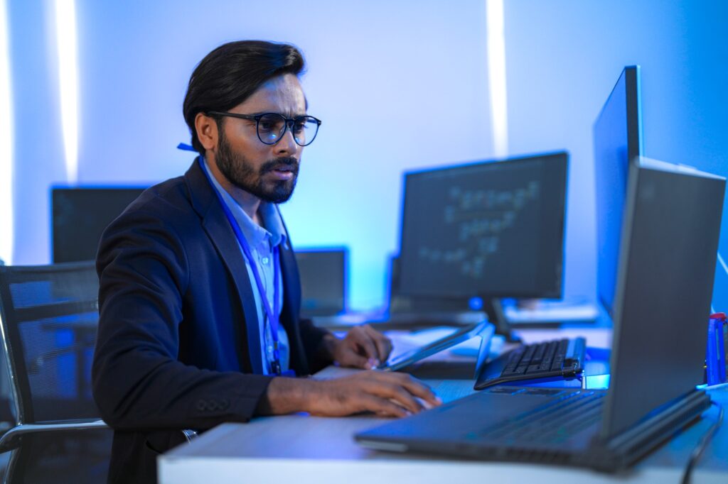 Focused Indian male AI developer coding a complex machine learning algorithm