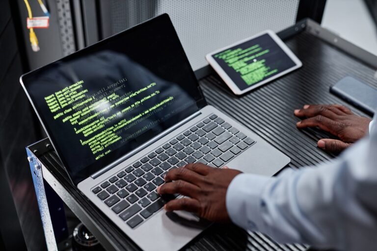 High angle network engineer or hacker using laptop in server room