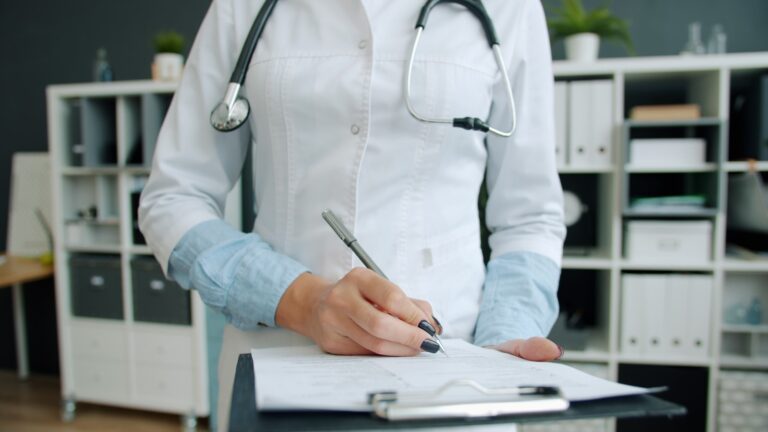 Doctor writing on clipboard in office